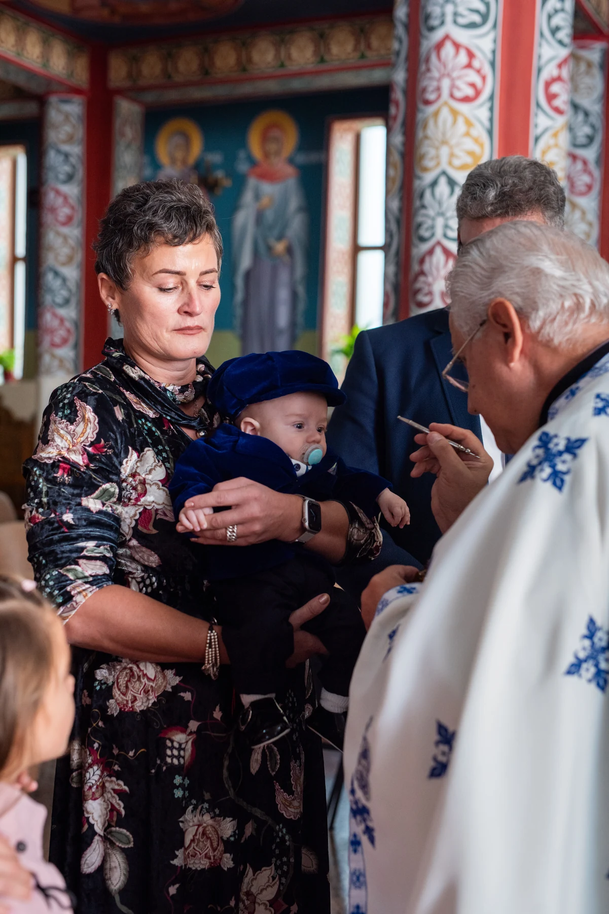 Bebeluș ținut în brațe în timpul ceremoniei de botez.