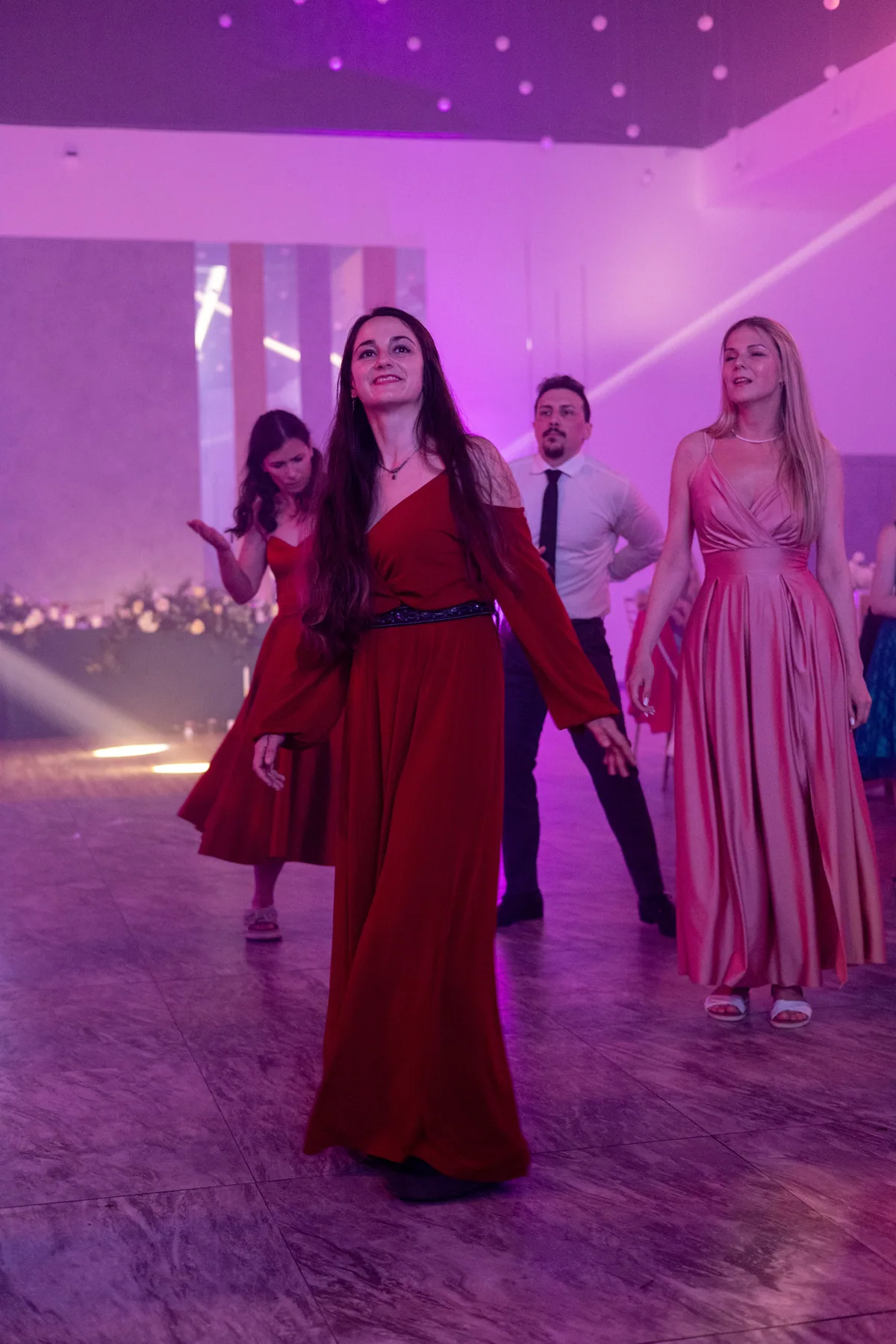 Invitate dansând sub lumina roz a petrecerii.